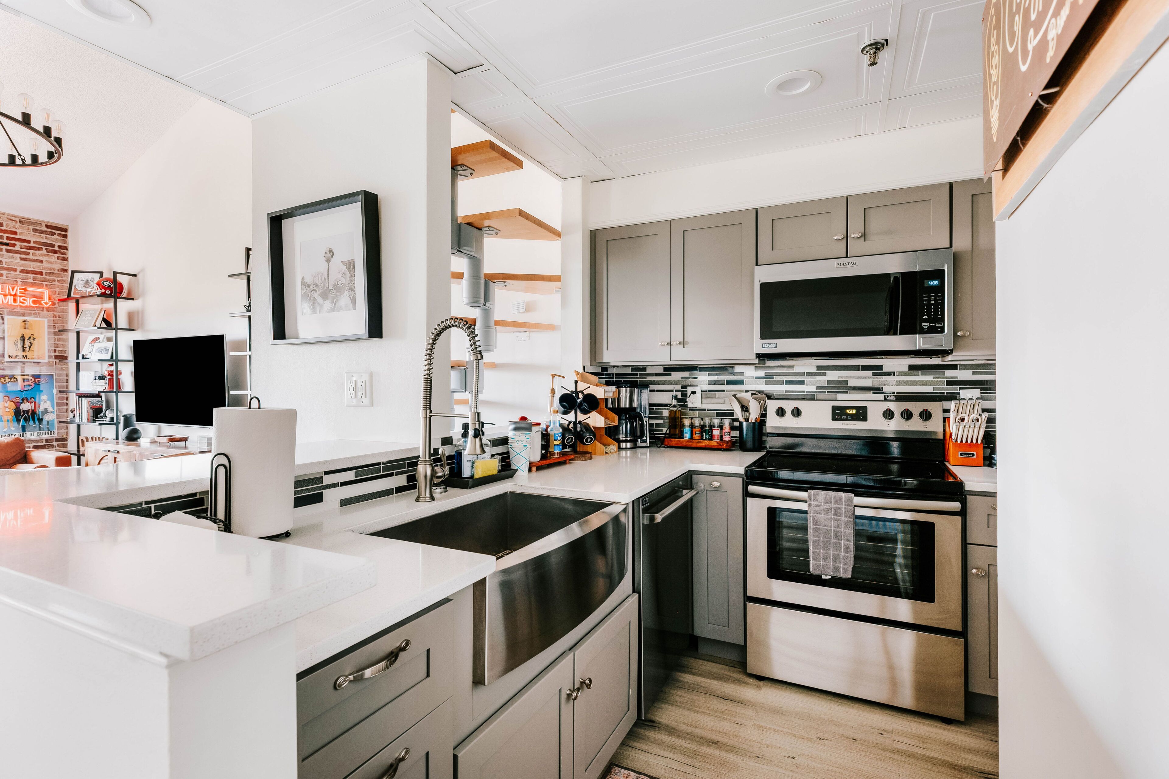 Una cocina moderna con electrodomésticos de acero inoxidable, una isla grande y un comedor con televisor de pantalla plana.