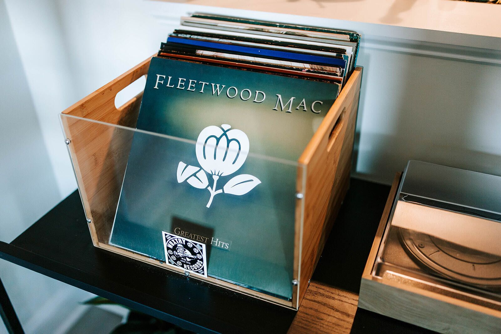 Una caixa de fusta amb l'etiqueta 'Fleetwood Mac' i un codi QR, que conté CDs o discos.