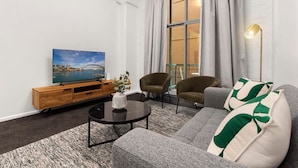 A modern living room with a sofa, armchairs, a coffee table, and a TV on a wooden console. - Heart of Darling Harbour (Pyrmont)
