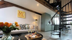 A modern living room with a sofa, a coffee table with food and drinks, a vase with flowers, and a staircase. - Spacious cosy apartment in historic building in the centre of charming Vianen (Vianen)