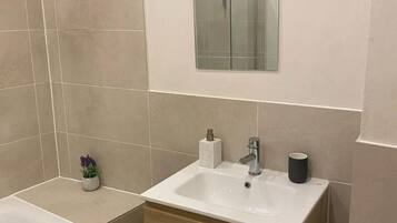 A modern bathroom with a large mirror, a sink, and a toilet.