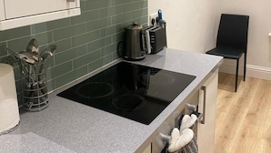 A modern kitchen with a black induction cooktop, stainless steel appliances, and a green tiled backsplash. - Stunning 1-bed Apartment in London (London)