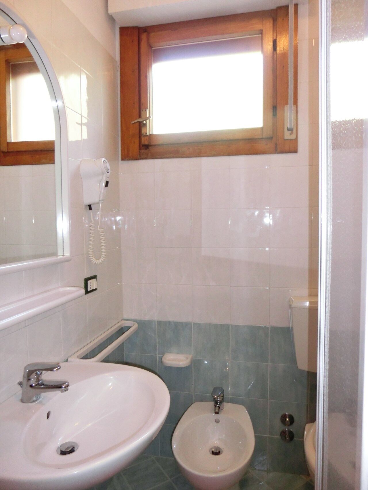 A bathroom with a white sink, a bidet, and a mirror.