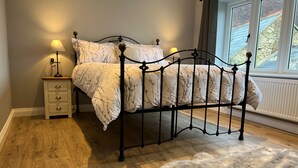 Une chambre à coucher avec un lit, des lampes de chevet, une table de chevet, un tapis en fourrure et une fenêtre avec des rideaux.