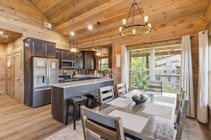 A wooden cabin interior with a kitchen, dining area, and large windows. - Little Bear Lodge 3 Bedroom Cabin by RedAwning (Sevierville)