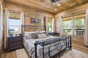 Ein Schlafzimmer einer Holzhütte mit Bett, Nachttischen und Deckenventilator.