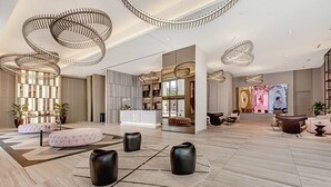 Eine großzügige Lobby mit modernem Design, ausgestattet mit einer zentralen Sitzecke, einem Empfangsbereich und einem großen Kunstwerk an der Wand.