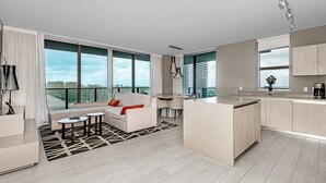 Eine moderne Wohnung mit Wohnbereich, Küche und großen Fenstern mit Blick auf die Stadt.