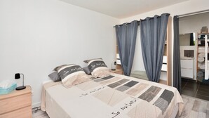 A bedroom with a bed, a nightstand, a desk, and a wardrobe.
