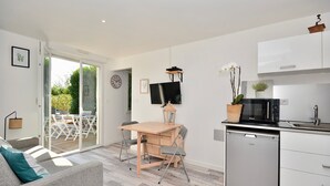 A modern kitchen with a dishwasher, a dining area with a table and chairs, and a sofa with a cushion.