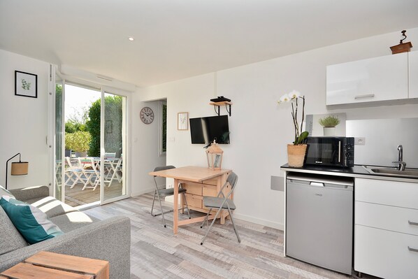 A modern kitchen with a dishwasher, a dining area with a table and chairs, and a sofa with a cushion.