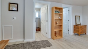 Un couloir avec une armoire en bois, un miroir et une porte donnant sur une autre pièce.