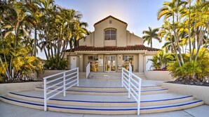 A building with a central entrance, a staircase leading up to the entrance, and a palm tree-lined pathway. - Sunny St Pete Getaway With Shared Pool & Hot Tub (St. Petersburg)