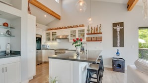 A modern kitchen with white cabinets, a central island, and hanging pendant lights.