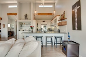 Uma cozinha moderna com ilha central, banquetas e objetos decorativos.