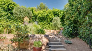 A garden with a wooden staircase leading up to a wooden deck.