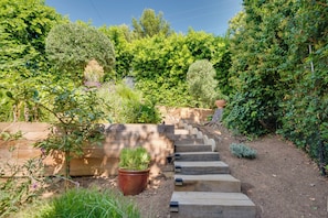 Um jardim com uma escadaria de madeira que leva a um deck de madeira.