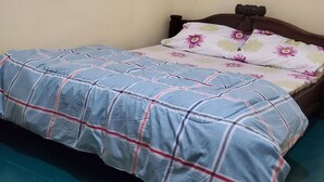 Un lit recouvert d’une couvre-lit à carreaux bleus et blancs, agrémenté de coussins à motifs floraux.
