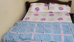 Un lit avec un drap du dessus à motifs floraux et un drap du dessous à carreaux bleus.