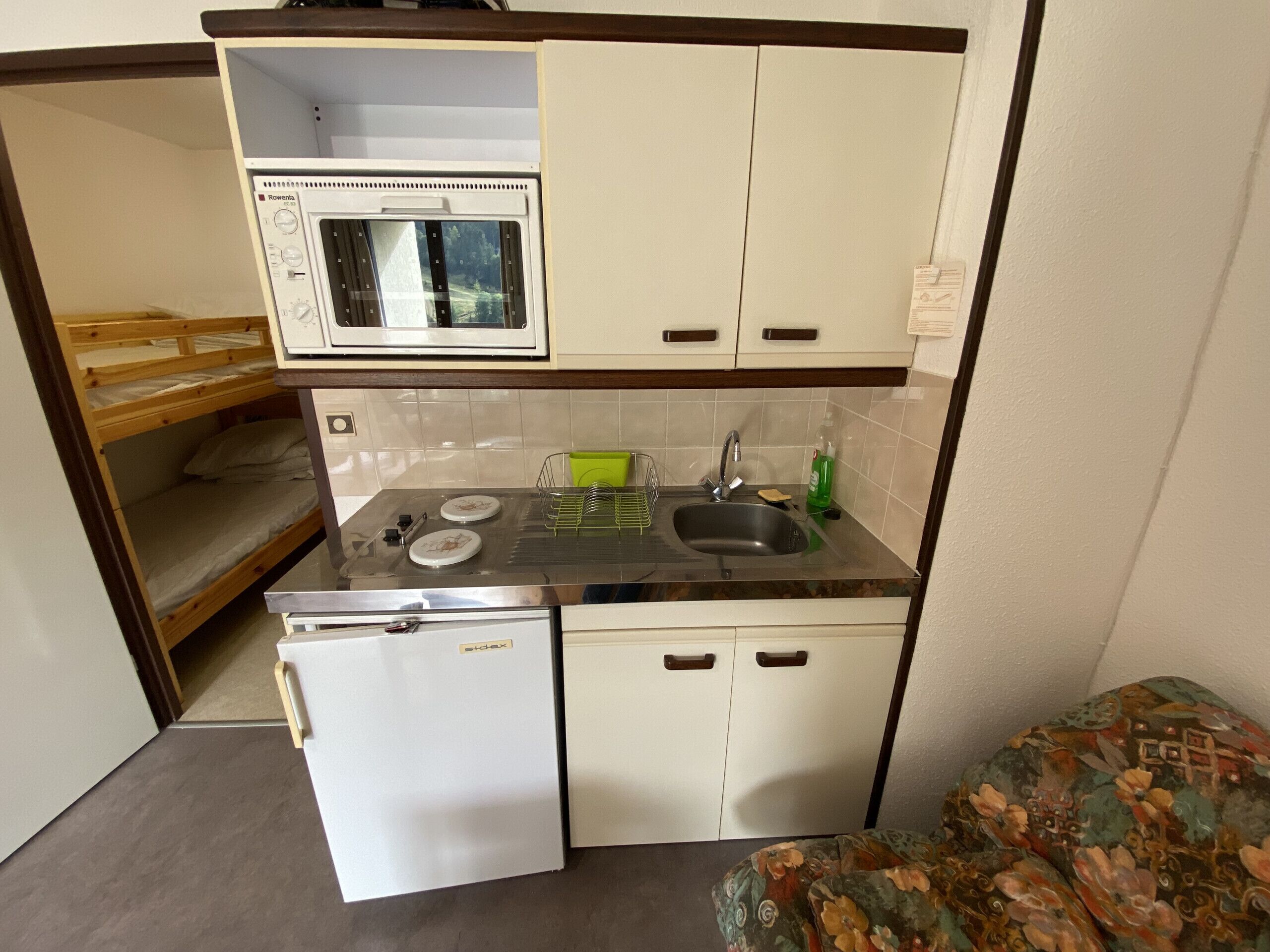 A compact kitchenette with a microwave, sink, and a small refrigerator.