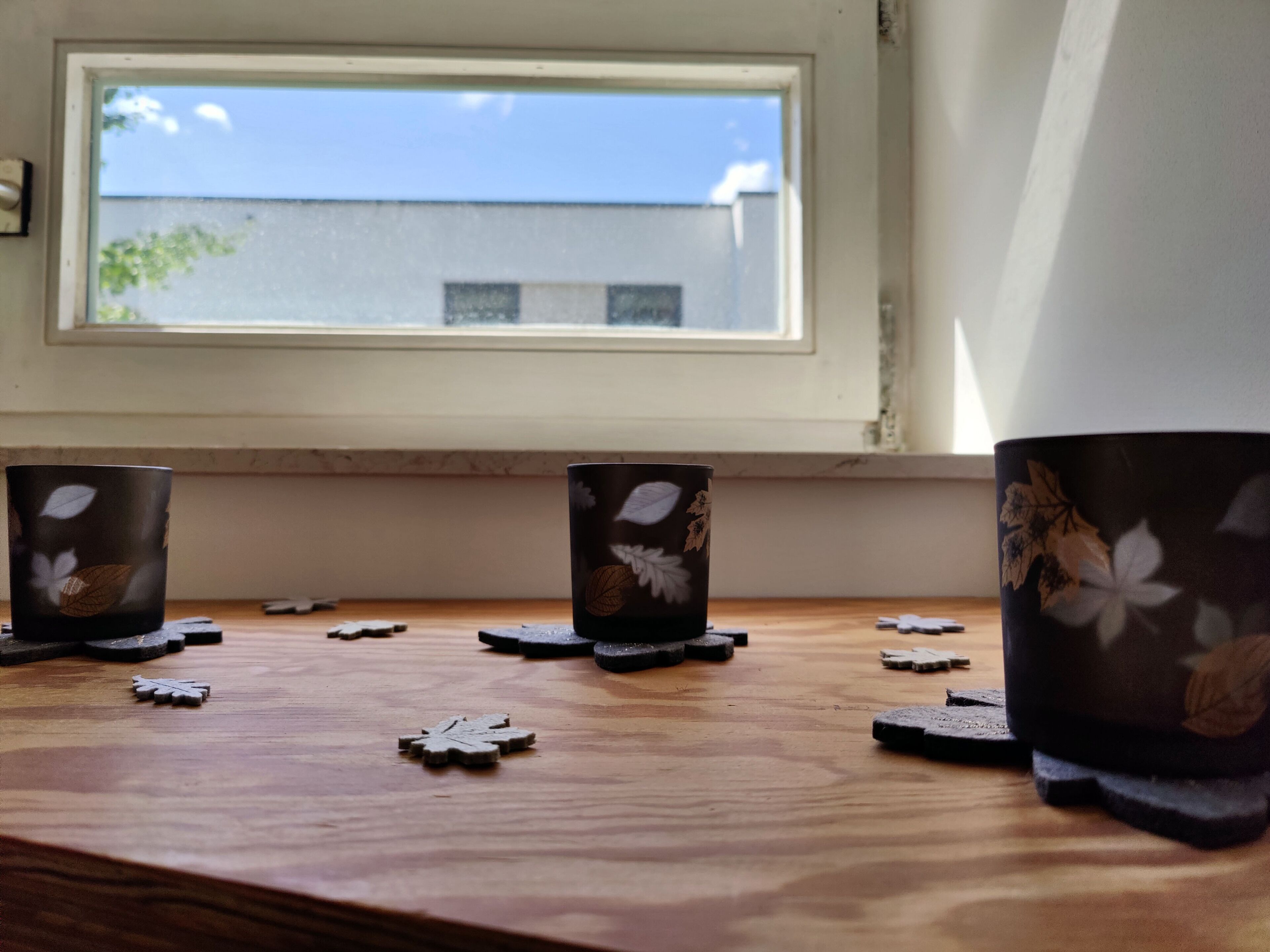 A wooden table with three decorative cups and a few small objects.