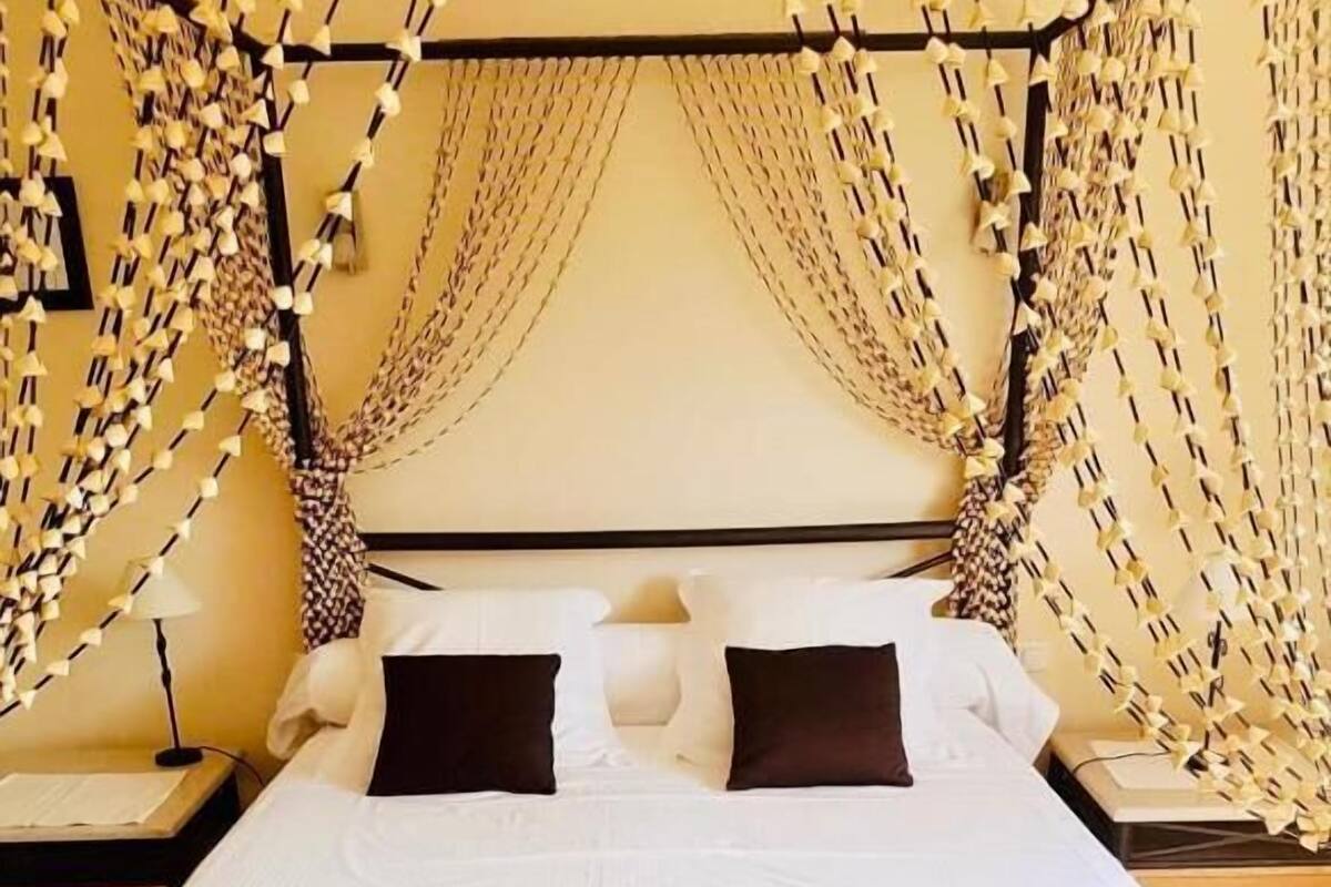 Una cama con cabecera oscura, ropa de cama blanca y dos almohadas negras.