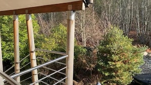 Un escalier en bois avec des rampes en métal mène à un bâtiment dont le toit est de couleur beige.
