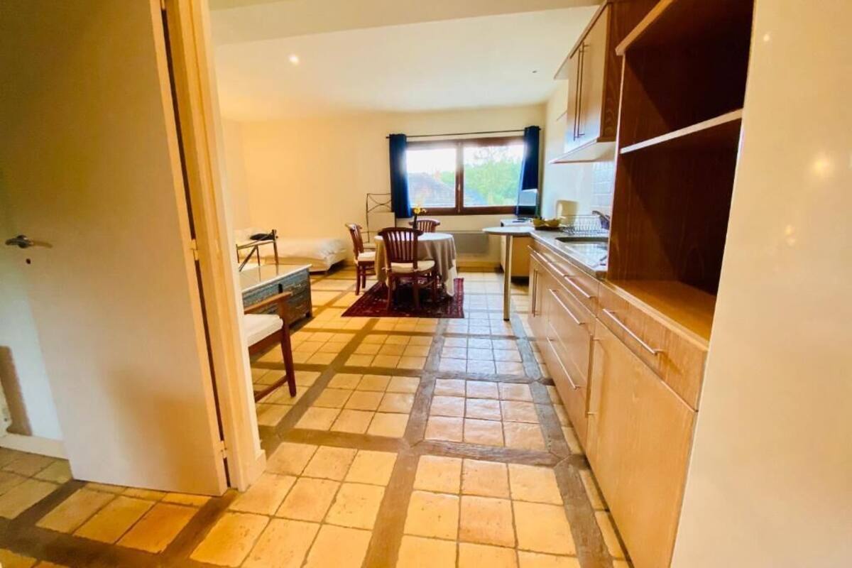 Una cocina compacta con comedor, una ventana con cortinas y suelo de baldosas.