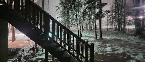 Una escalera de madera que conduce a un edificio en un bosque nevado.