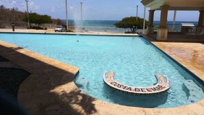 A pool with a 'Costa Del Mar' sign, a gazebo, and a view of the ocean. - Your Cozy Combate beach retreat, 2 bed/2bath, full A/C, free laundry (Combate)