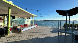 A wooden deck with outdoor seating, a covered area, and a view of the water. - Your Cozy Combate beach retreat, 2 bed/2bath, full A/C, free laundry (Combate)