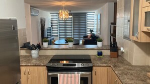 A modern kitchen with a built-in oven, stainless steel refrigerator, and granite countertops. - Your Cozy Combate beach retreat, 2 bed/2bath, full A/C, free laundry (Combate)