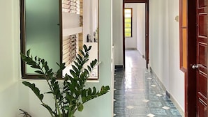 A hallway with a potted plant, a fire extinguisher, and a tiled floor. - Shine Homestay Hue (Hue)