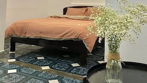 A bedroom with a bed, a vase with flowers, and a tiled floor. - Shine Homestay Hue (Hue)
