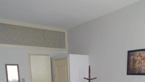 A bedroom with a bed, a wardrobe, a mirror, and a painting on the wall. - hotel minas salvador (Salvador)