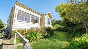 A two-story house with a front yard, a wooden fence, and a metal gate.