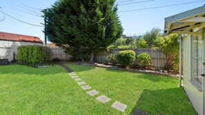 Enjoy a serene escape in our beautifully maintained backyard with a tranquil lawn and stone pathway.