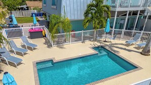 A rectangular pool with a white fence, lounge chairs, and umbrellas. - A Perfect Get-Away! Newly Remodeled Home On Siesta Key! (Siesta Key)