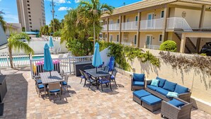 A patio area with outdoor furniture, a pool, and a building with balconies. - A Perfect Get-Away! Newly Remodeled Home On Siesta Key! (Siesta Key)