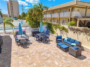 A patio area with outdoor furniture, a pool, and a building with balconies.