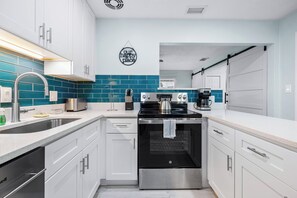 A modern kitchen with white cabinets, a stainless steel range, and a blue tiled backsplash.