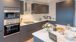 Una cocina moderna con electrodomésticos de acero inoxidable, encimera de mármol y pileta integrada.