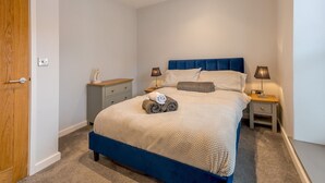 Un dormitorio con cama, dos mesitas de noche, un armario y un enchufe en la pared.