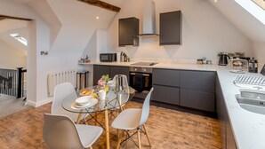 A modern kitchen with a large island, dark cabinetry, and a skylight. - 5C Charming Town Centre Apartment With Roof Top Views - Pass the Keys (Shrewsbury)