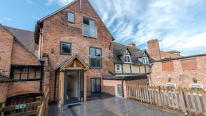 A two-story brick house with a wooden deck, a fire exit sign, and a chimney. - 5C Charming Town Centre Apartment With Roof Top Views - Pass the Keys (Shrewsbury)
