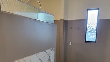 Ein modernes Badezimmer mit einer großen Badewanne, Marmorfliesen und einem kleinen Fenster mit dekorativem Sichtschutz.