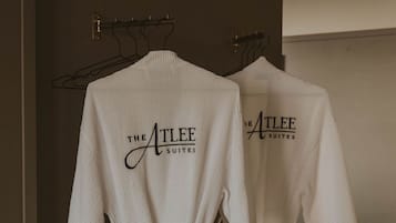 Twee witte jassen hangen aan een rek, met de tekst 'THE ATLEE SUITES' zichtbaar op de achterkant.