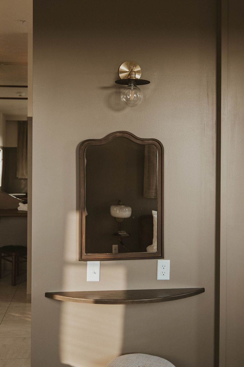 A bathroom with a wall-mounted mirror, a sink, and a light fixture above the mirror.