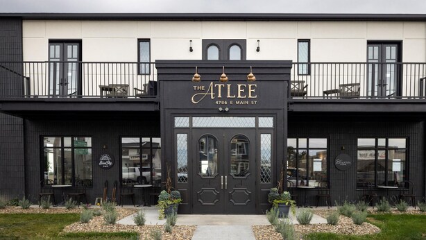 A building with a black facade, a double door entrance, and outdoor seating areas. - The Atlee Suites (Berlin)