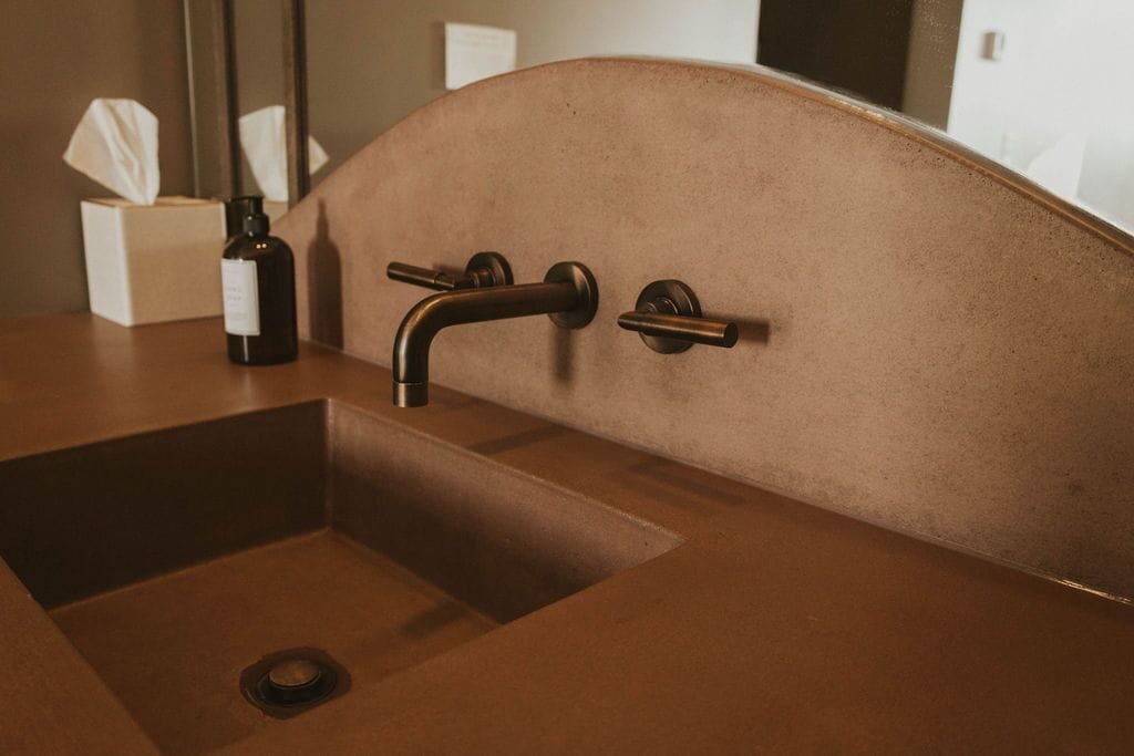 A bathroom sink with a copper finish, a mirror, and a tissue box.